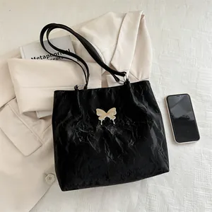Minimalist black pleated tote bag with butterfly detail on stylish lifestyle background