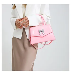 Detail of pink patent leather handbag with silver butterfly clasp shown on model