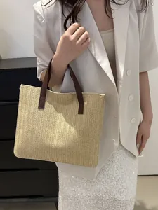 Close-up of woven straw tote bag featuring herringbone texture and brown leather straps