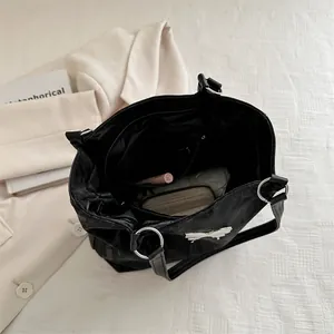 Minimalist black tote bag with bow detail and chain strap showing large interior capacity
