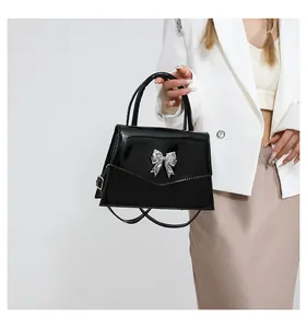 Detail of glossy black patent leather handbag with a sparkling silver rhinestone butterfly