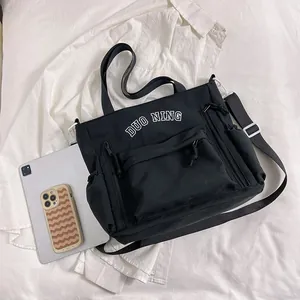 Large black canvas tote bag with multi-pocket design and adjustable shoulder strap
