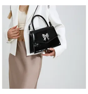 Polished black patent leather handbag featuring a silver butterfly metallic buckle