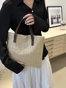 Detail of hand-woven straw tote with brown leather handles and herringbone weave pattern