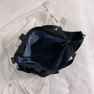 Large capacity black nylon tote bag with blue lining and secure zipper closure for travel