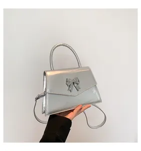 Detailed close-up of a metallic silver crossbody bag with a 3D butterfly decoration