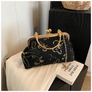 Detail of vintage shell bag with gold butterfly embroidery and metal clasp handle