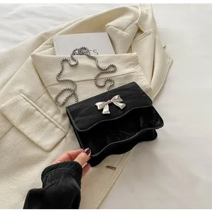 Detail of black wave texture bag featuring silver bow metal buckle and chain strap