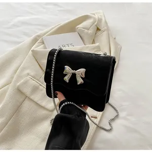 Close-up of black velvet shoulder bag with wavy flap and silver metal bow detail