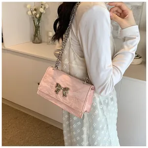 Détail du sac en cuir plissé rose clair avec nœud en métal argenté et bandoulière