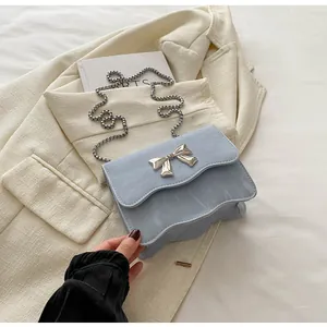 Close-up of light blue handbag with wave edge, silver bow buckle and chain strap