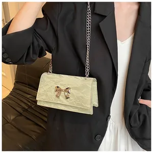 Détail du sac à bandoulière vert clair avec texture en cuir froissé et boucle nœud doré