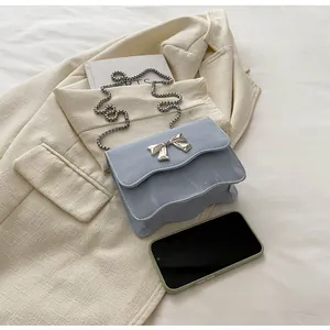 Close-up of light blue handbag with silver bow buckle and elegant metal chain strap