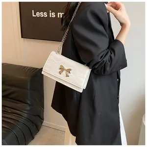 Détail du sac bandoulière blanc perle avec texture plissée et fermoir nœud doré
