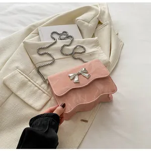 Detail of pink marble-textured crossbody bag featuring a silver bow clasp and chain strap
