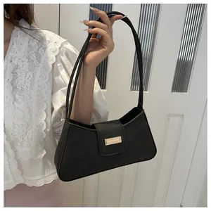Detail of a chic black baguette bag with gold buckle hardware and fine leather texture