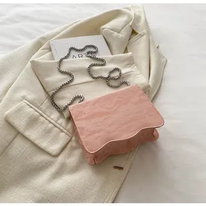 Detail showing pink pleated texture bag with wavy bottom and silver chain strap