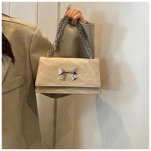Détail du sac à bandoulière plissé beige avec boucle nœud en métal argenté et chaîne