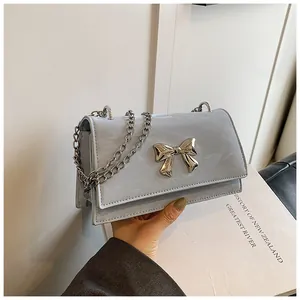 Détail du sac à main bleu clair texture marbre avec nœud argenté et bandoulière chaîne