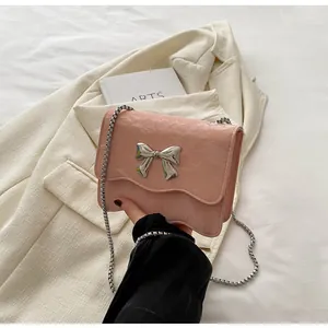 Detail of light pink patent leather bag featuring silver bow and wavy flap edge