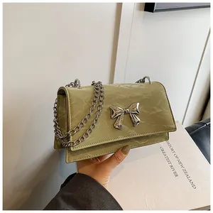 Détail d'un sac à main vert clair texture marbre avec nœud argenté et bandoulière chaîne