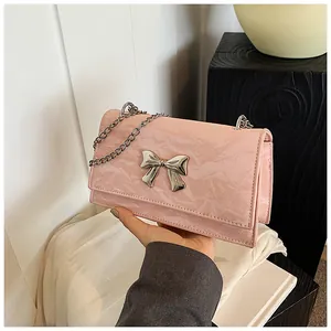 Détail du sac en cuir plissé rose brillant avec un nœud en métal argenté et une chaîne