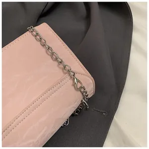 Détail du sac à main à motif marbre rose avec cuir brillant et bandoulière chaîne