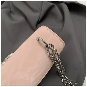 Détail de la texture marbre rose et bandoulière chaîne argentée d'un sac chic