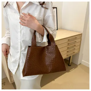 Detail of a brown woven texture tote bag featuring a minimalist faux leather structure