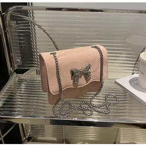 Close-up of pink pleated leather bag with a silver metal bow buckle and chain strap