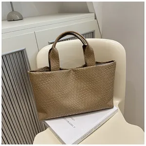 Detail of a brown woven bucket bag with intricate cross-weave texture and sturdy handle