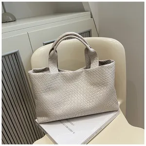Detailed close-up of beige woven bucket bag featuring intricate Intrecciato craft textures