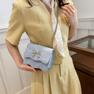 Light blue wave-edge crossbody bag with silver bow accent and metal chain strap