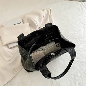 Black woven large capacity bucket bag in intrecciato style with items inside