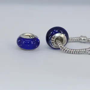 Detail of dark blue glass charm bead with white polka dots and S925 silver core on snake chain