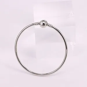 Bracelet jonc argenté poli avec fermoir sphérique sur support en acrylique clair