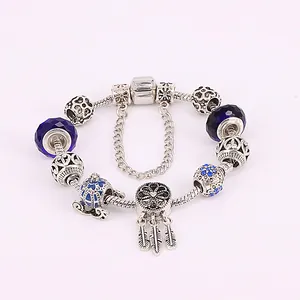 Detalle macro de pulsera de plata con abalorios de vidrio azul y colgante de carruaje