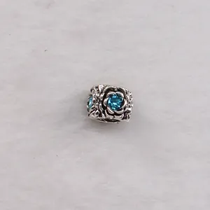 Vintage silver rose charm bead with sea blue crystal center on white plush backdrop