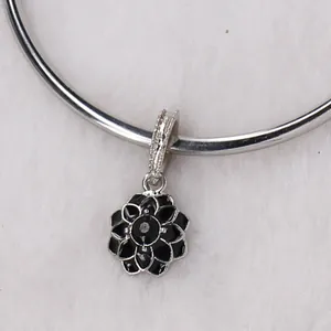 Macro shot of black enamel flower charm with zircon center on silver charm bracelet