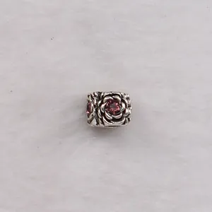 Macro detail of silver floral bead with embossed roses and a purple zircon gemstone