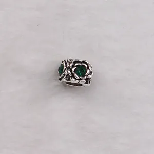 Macro view of rose shaped alloy charm bead with green crystals for DIY bracelets