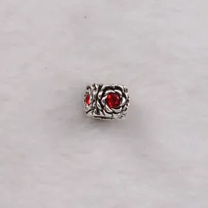 Macro detail of antique silver rose bead with a vibrant red crystal for DIY bracelets