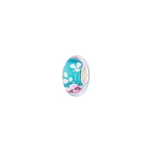 Macro detail of turquoise glass charm bead with pink flower petals and metal core