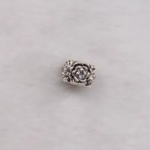 Macro shot of silver petal charm with sparkling center stone on white faux fur background