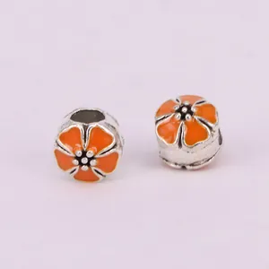 Detail of two orange enamel cherry blossom charms with silver metal for DIY jewelry