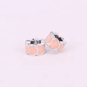 Macro view of silver alloy hollow charms with pink heart-shaped enamel pattern