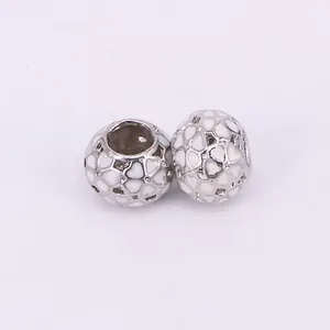 Detailed view of silver heart charms with white enamel dots for DIY jewelry making