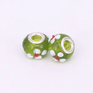 Macro detail of green glass beads with handmade floral patterns and silver metal cores