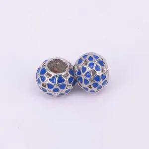 Macro view of silver alloy flower beads with blue enamel hollow heart patterns