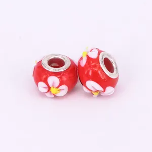 Detailed macro of two red lampwork glass beads with white flowers and silver metal cores